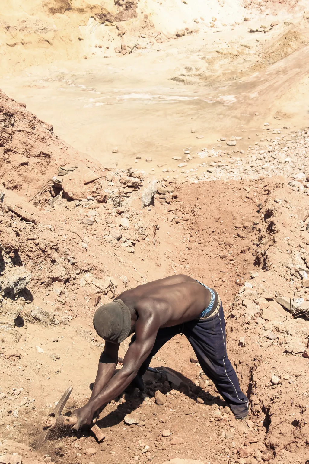 un homme de couleur dans une carrière avec une pioche à la main